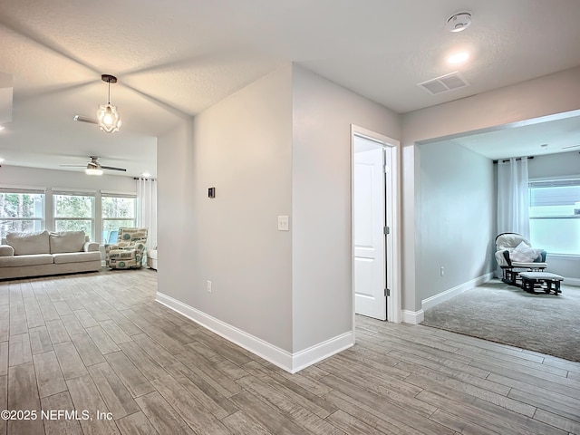 hallway with visible vents, baseboards, and wood finished floors