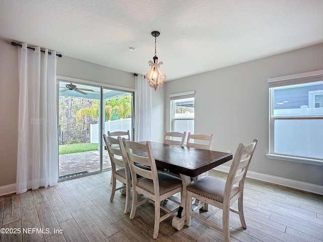 dining space featuring a textured ceiling, light wood-type flooring, and baseboards