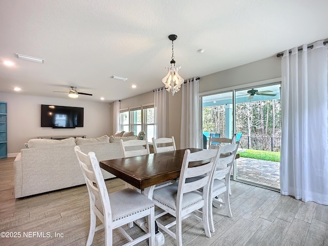 dining area featuring a textured ceiling, ceiling fan with notable chandelier, baseboards, and light wood-style floors