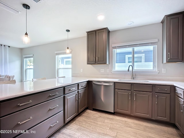 kitchen featuring a sink, light wood-style floors, light countertops, dishwasher, and pendant lighting