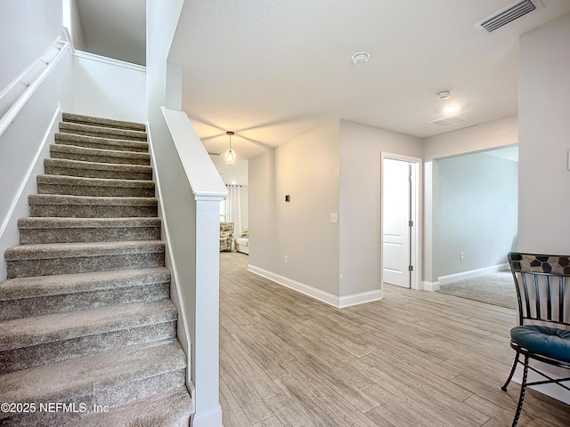 staircase featuring baseboards, visible vents, and wood finished floors