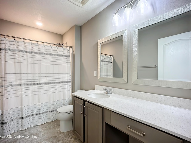 bathroom featuring a shower with shower curtain, vanity, toilet, and a textured ceiling