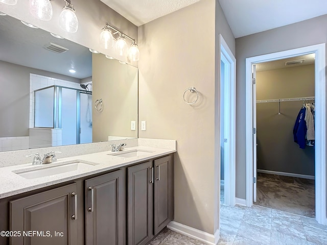 bathroom with a walk in closet, a sink, visible vents, and a shower stall