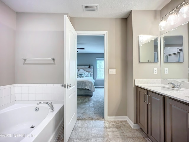 bathroom featuring visible vents, connected bathroom, a textured ceiling, vanity, and a bath