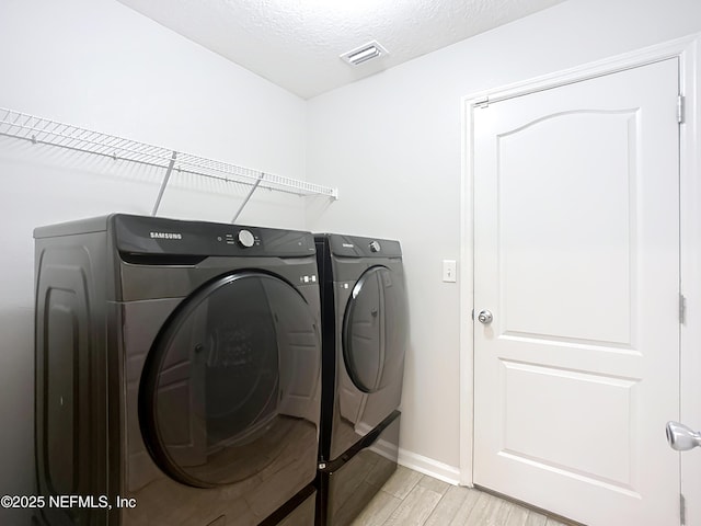 washroom with laundry area, independent washer and dryer, a textured ceiling, and light wood finished floors