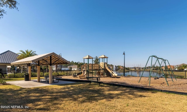 communal playground with a lawn, a water view, and fence