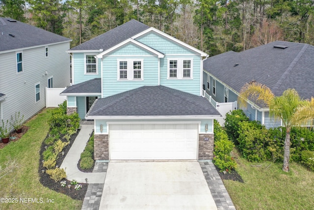 view of front of home featuring stone siding, a shingled roof, an attached garage, and driveway