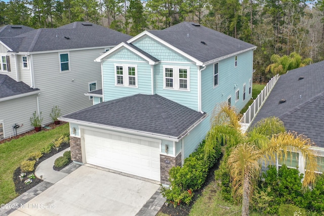 view of front facade featuring a garage, stone siding, a shingled roof, and concrete driveway