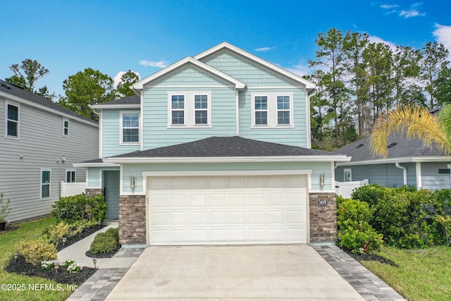 view of front of home featuring an attached garage, stone siding, a shingled roof, and concrete driveway