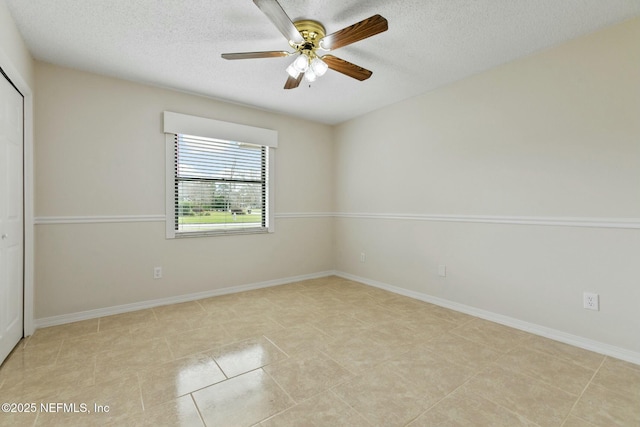 spare room featuring a textured ceiling, tile patterned floors, a ceiling fan, and baseboards