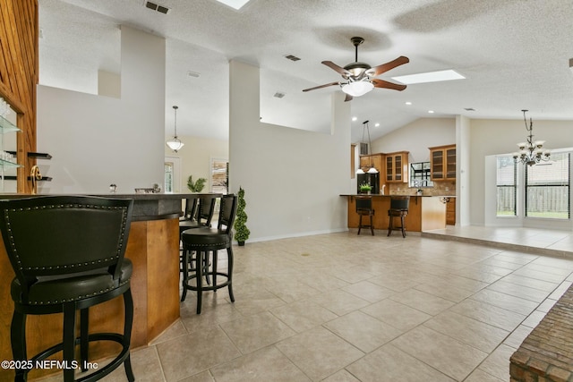 interior space featuring light tile patterned floors, ceiling fan with notable chandelier, visible vents, and decorative light fixtures