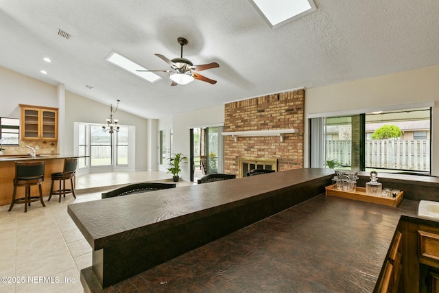 kitchen with lofted ceiling with skylight, visible vents, plenty of natural light, and a kitchen breakfast bar