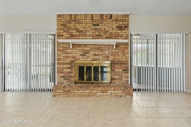 unfurnished living room with a brick fireplace, tile patterned flooring, and a textured ceiling