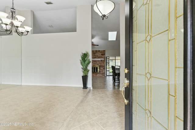 foyer featuring a fireplace, tile patterned flooring, visible vents, and an inviting chandelier