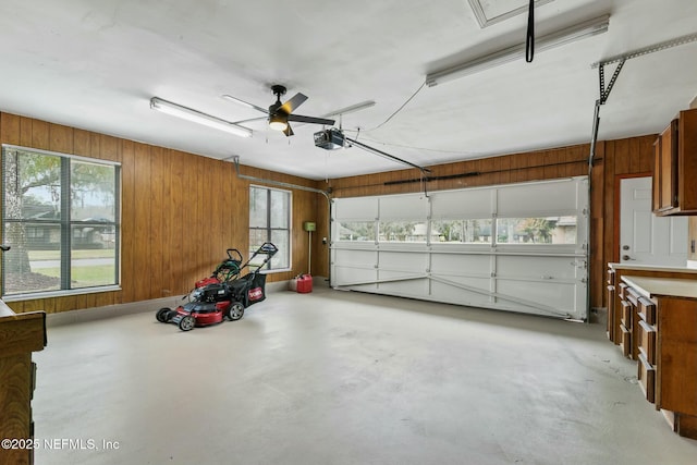 garage with ceiling fan, wood walls, and a garage door opener