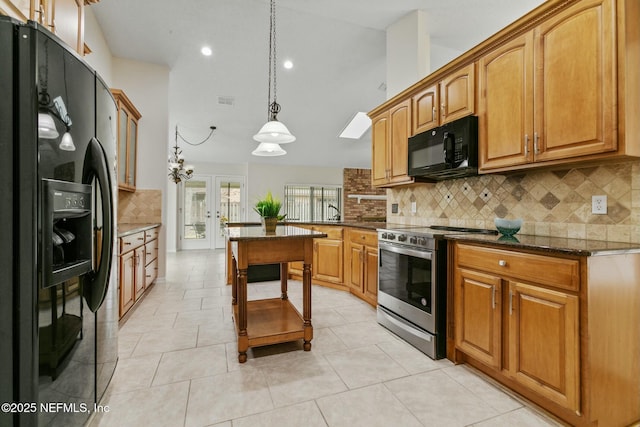 kitchen featuring light tile patterned floors, vaulted ceiling, backsplash, black appliances, and dark stone countertops