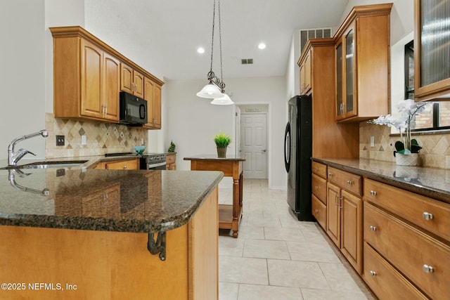 kitchen featuring visible vents, brown cabinetry, a peninsula, black appliances, and a sink