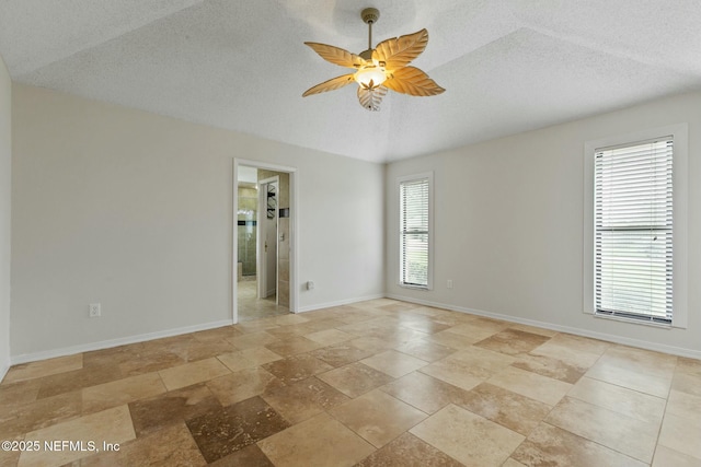 spare room with a ceiling fan, a textured ceiling, and baseboards