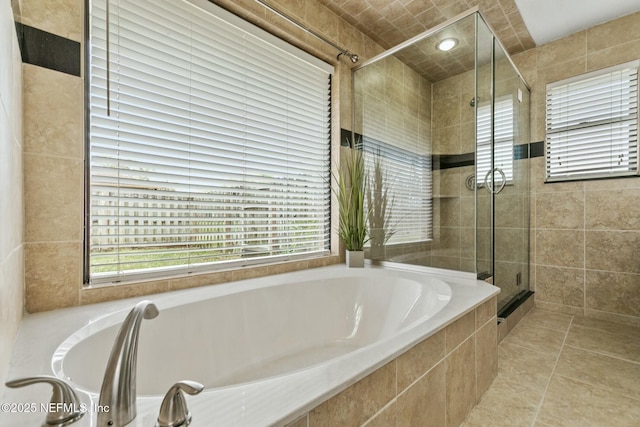 bathroom with a stall shower, tile patterned flooring, a garden tub, and a wealth of natural light