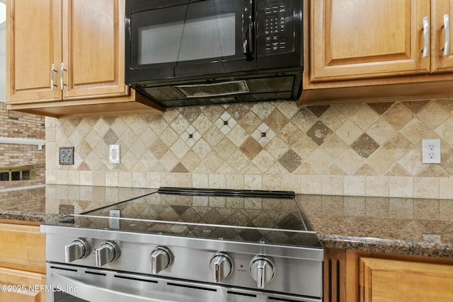 kitchen with tasteful backsplash, black microwave, dark stone counters, and stainless steel range with electric cooktop