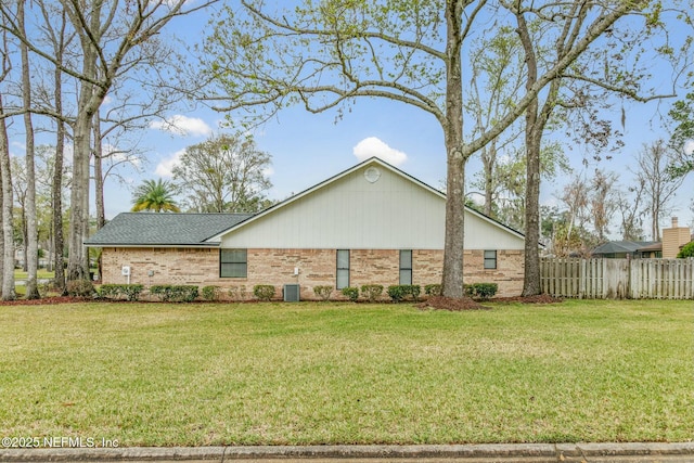 view of home's exterior featuring a yard, a shingled roof, fence, and brick siding