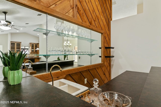 interior space featuring vaulted ceiling, indoor wet bar, a sink, and a ceiling fan