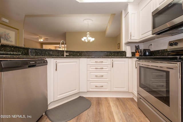 4020 Lavista Cir Unit 207, Jacksonville, FL 32217 - kitchen featuring light wood finished floors, stainless steel appliances, white cabinetry, a sink, and dark stone countertops