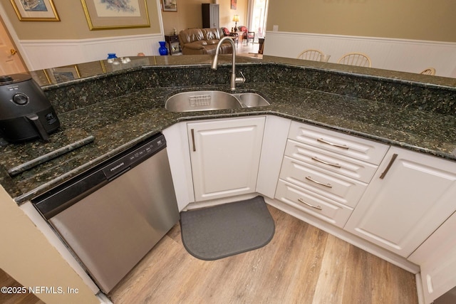 4020 Lavista Cir Unit 207, Jacksonville, FL 32217 - kitchen with wood finished floors, a sink, white cabinetry, stainless steel dishwasher, and wainscoting