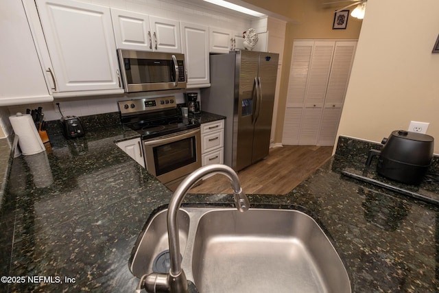 4020 Lavista Cir Unit 207, Jacksonville, FL 32217 - kitchen with stainless steel appliances, wood finished floors, a sink, white cabinets, and dark stone countertops