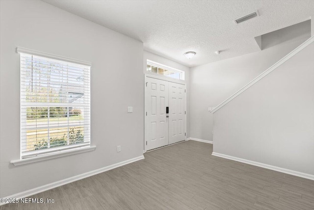 foyer with plenty of natural light, wood finished floors, visible vents, and baseboards