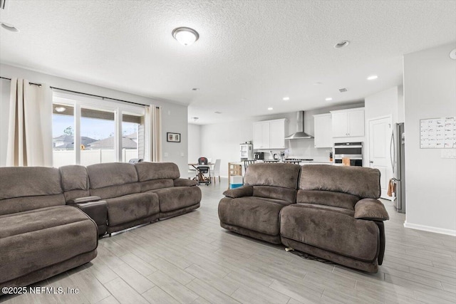 living room with light wood-type flooring, a textured ceiling, baseboards, and recessed lighting