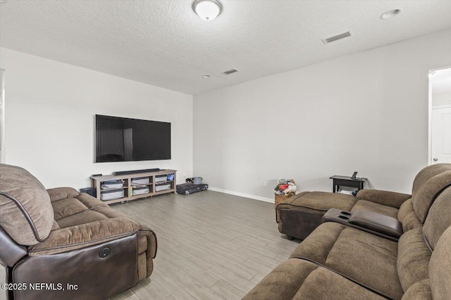 living area with visible vents, a textured ceiling, baseboards, and wood finished floors