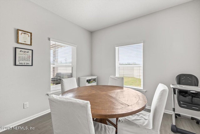 dining space featuring dark wood-style floors, a wealth of natural light, and baseboards