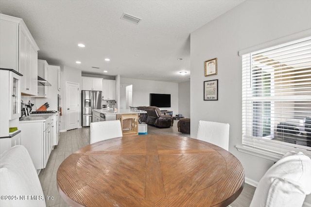 dining room with light wood-style floors, recessed lighting, visible vents, and baseboards