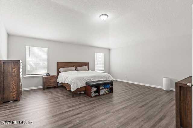 bedroom featuring baseboards, dark wood finished floors, and a textured ceiling