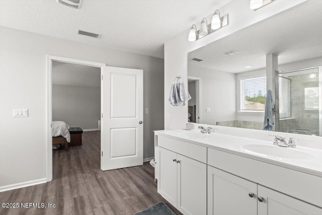 bathroom with a stall shower, a textured ceiling, a sink, and wood finished floors