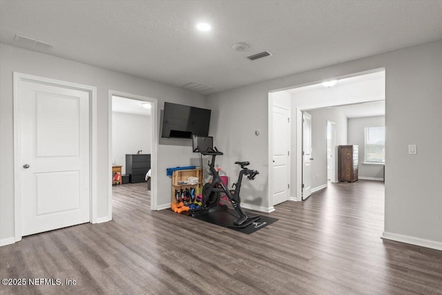 exercise area featuring visible vents, baseboards, and wood finished floors