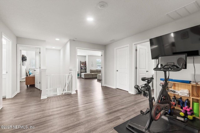 workout area featuring a textured ceiling, recessed lighting, wood finished floors, visible vents, and baseboards