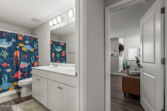 full bath with a textured ceiling, wood finished floors, a sink, and visible vents