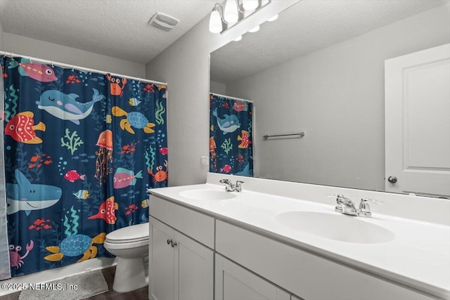 full bathroom featuring double vanity, visible vents, toilet, a textured ceiling, and a sink