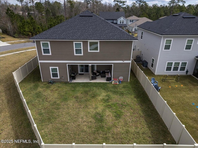 back of house with a yard, roof with shingles, a patio area, and a fenced backyard