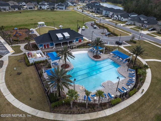 community pool with a patio area, fence, and a residential view