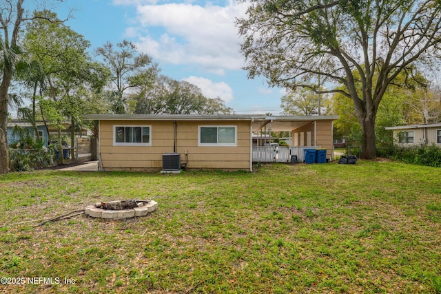 back of house featuring a yard, a fire pit, central AC unit, and fence