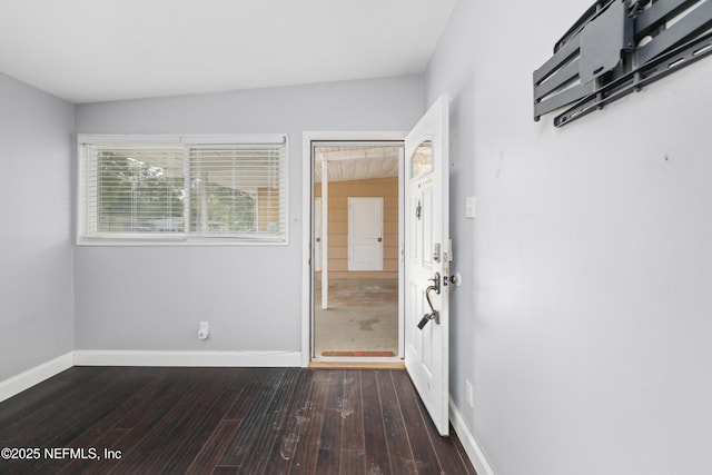 unfurnished room featuring baseboards and dark wood-style flooring