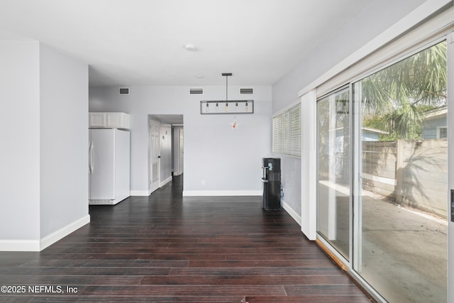 unfurnished living room featuring dark wood-style flooring, visible vents, and baseboards