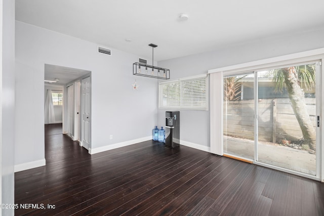 unfurnished living room with visible vents, dark wood finished floors, and baseboards