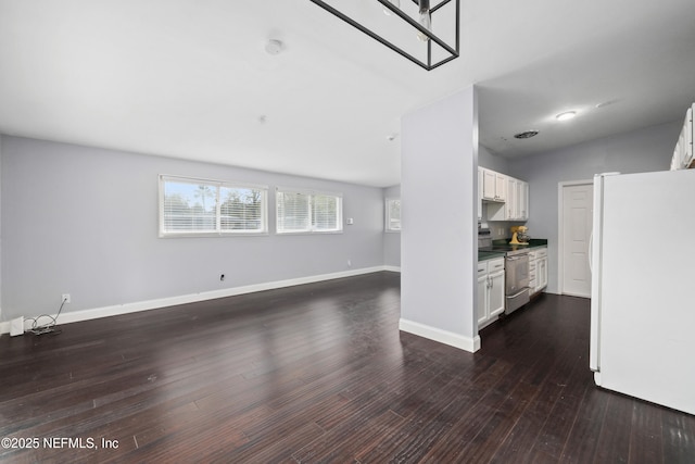 unfurnished living room featuring dark wood-style floors, vaulted ceiling, and baseboards