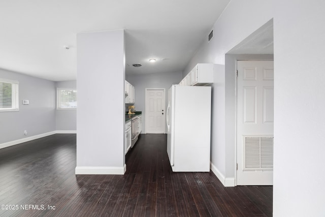 hall featuring dark wood-type flooring, visible vents, and baseboards