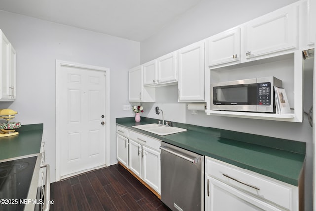 kitchen featuring dark wood-style flooring, stainless steel appliances, dark countertops, white cabinets, and a sink