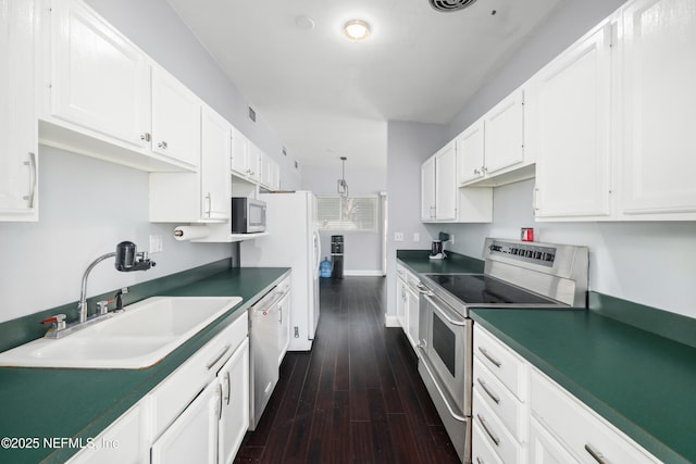 kitchen with white cabinets, dark countertops, dark wood-style floors, appliances with stainless steel finishes, and a sink